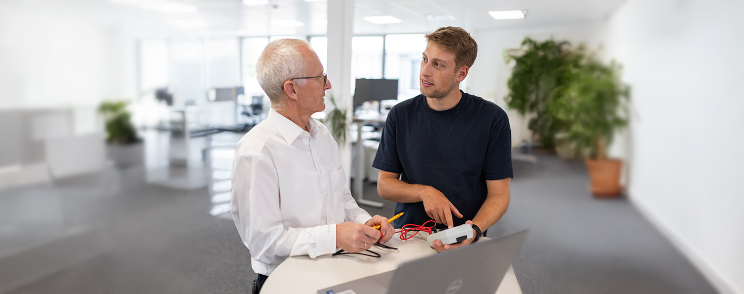 Two men look at an electrical test device and adjust values on it Process Consulting for Test Equipment Management
