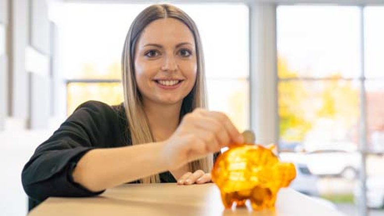 Testo offers various options for financial security. A Testo employee feeds his piggy bank with money.